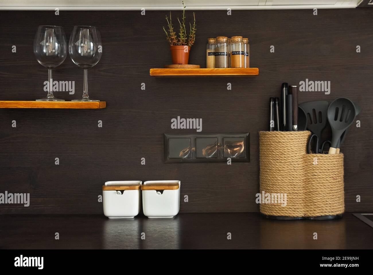 Kitchen utensils, decor, jars with spice, knives. glasses and plant in a modern scandinavian style interior. Kitchen objects on the shelf and table Stock Photo