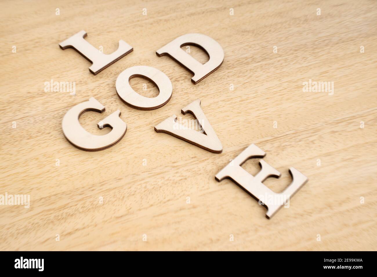 God is Love concept. Words forming a cross on wooden table. Selective focus Stock Photo
