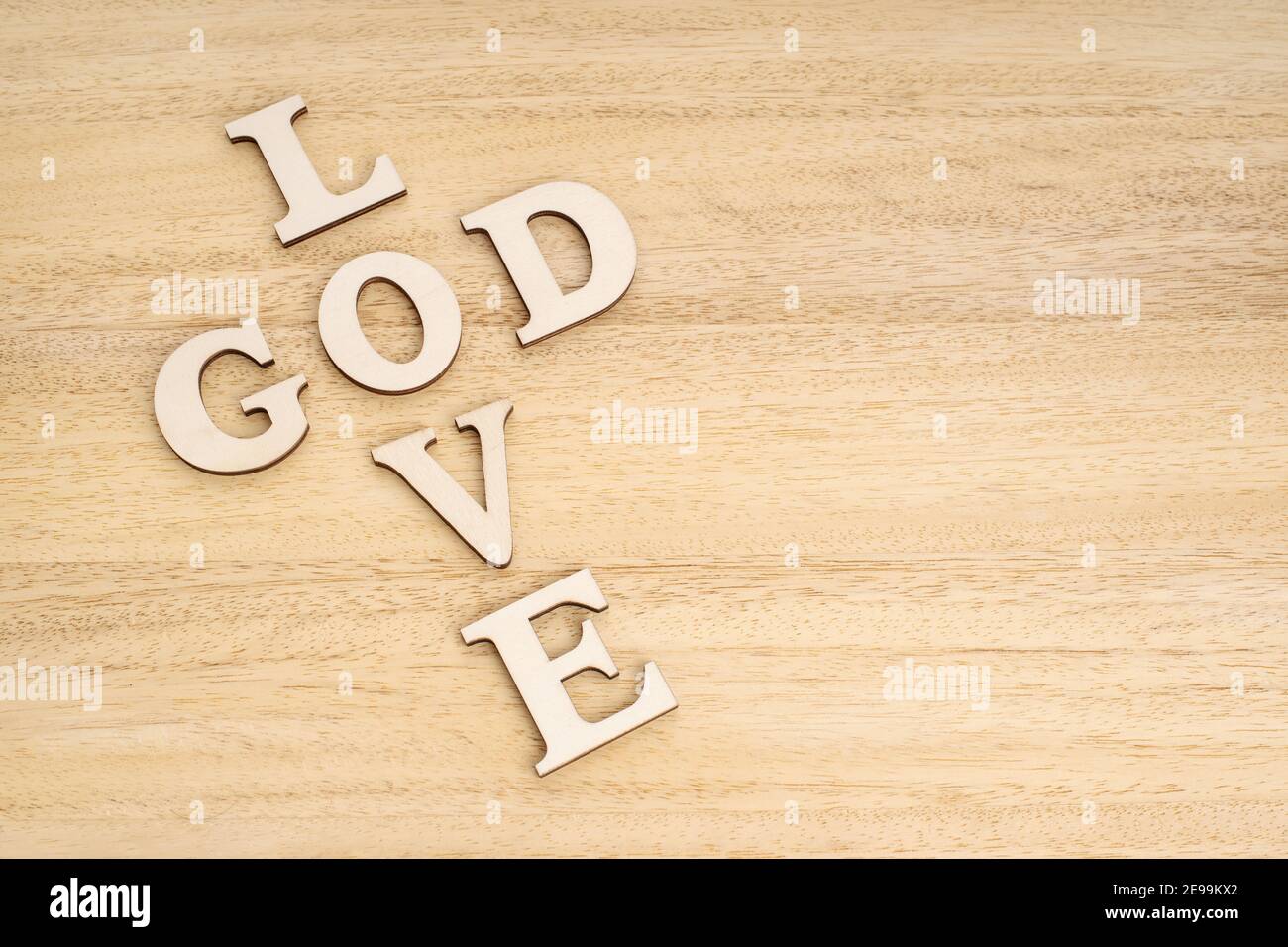 God is Love concept. Words forming a cross on wooden table. Copy space Stock Photo