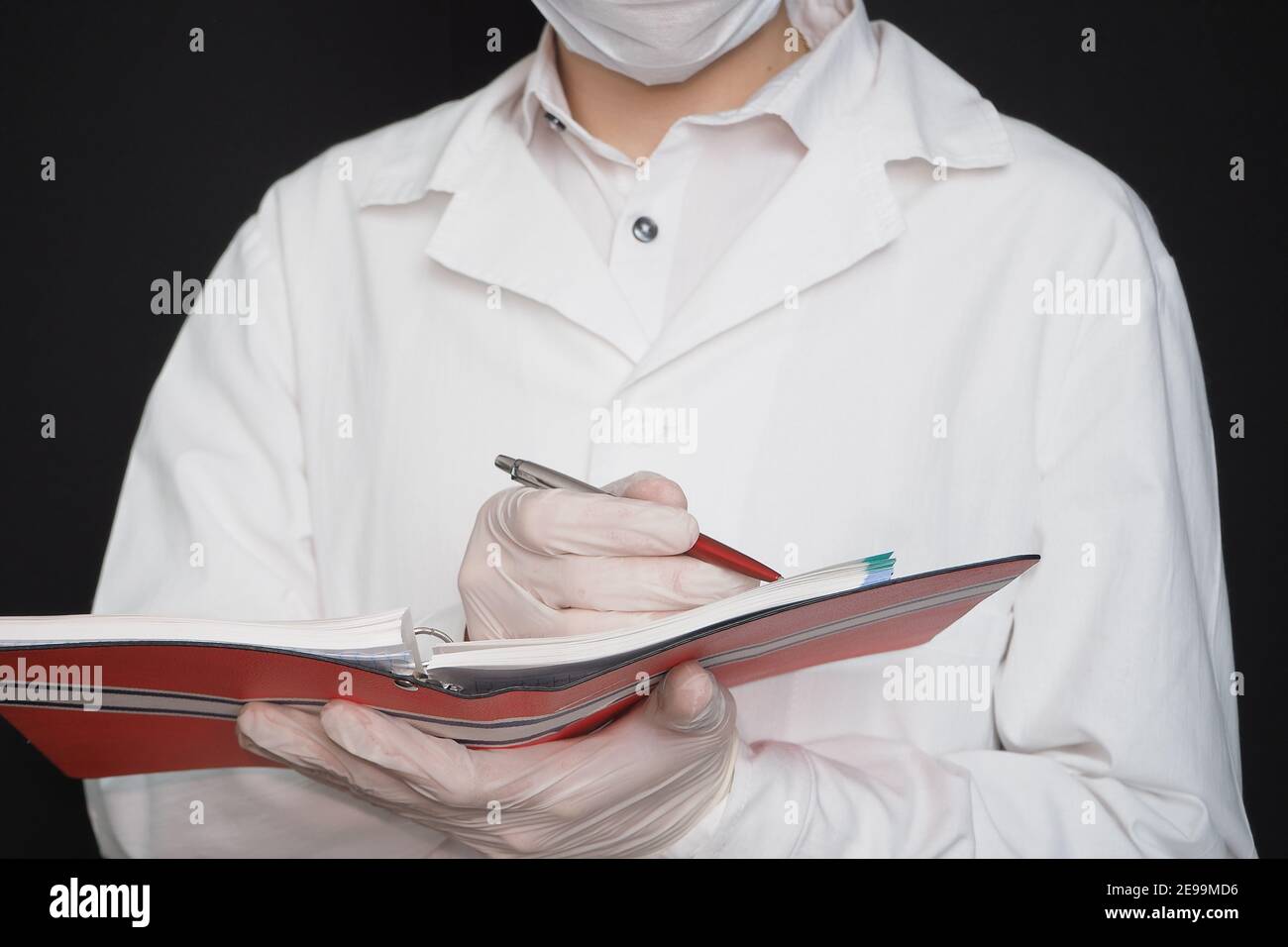 Science and medicine, a doctor in special clothes mask and rubber gloves with a notebook in his hands. Stock Photo