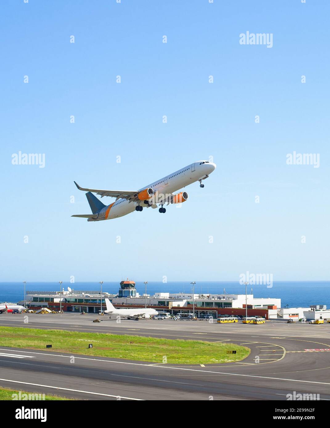 Airplane taking off International Airport skyward view, planes parked by terminal, sunshine, seascape, Funchal, Madeira Stock Photo