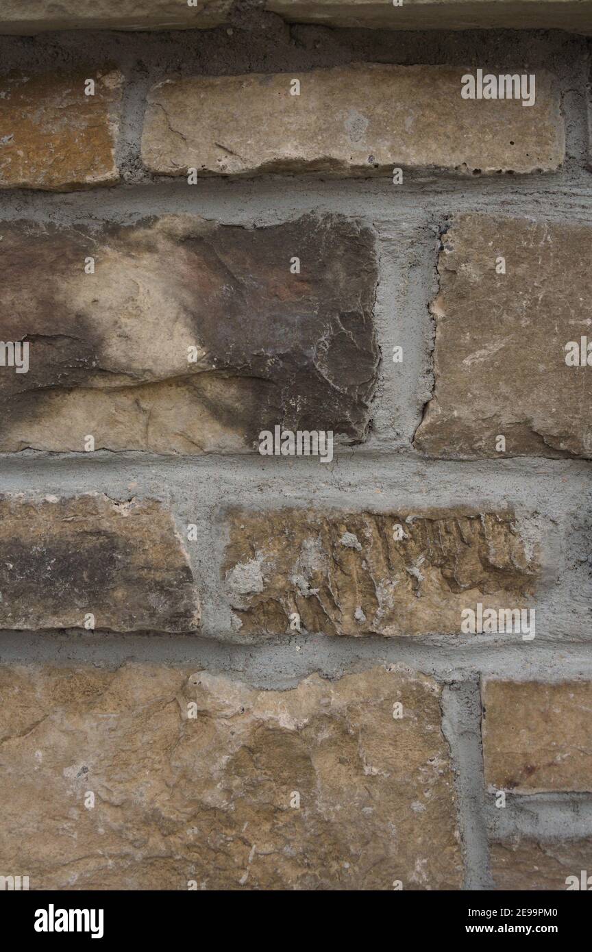 Close-up photo of a rough, natural-stone wall with gray grout. Stock Photo