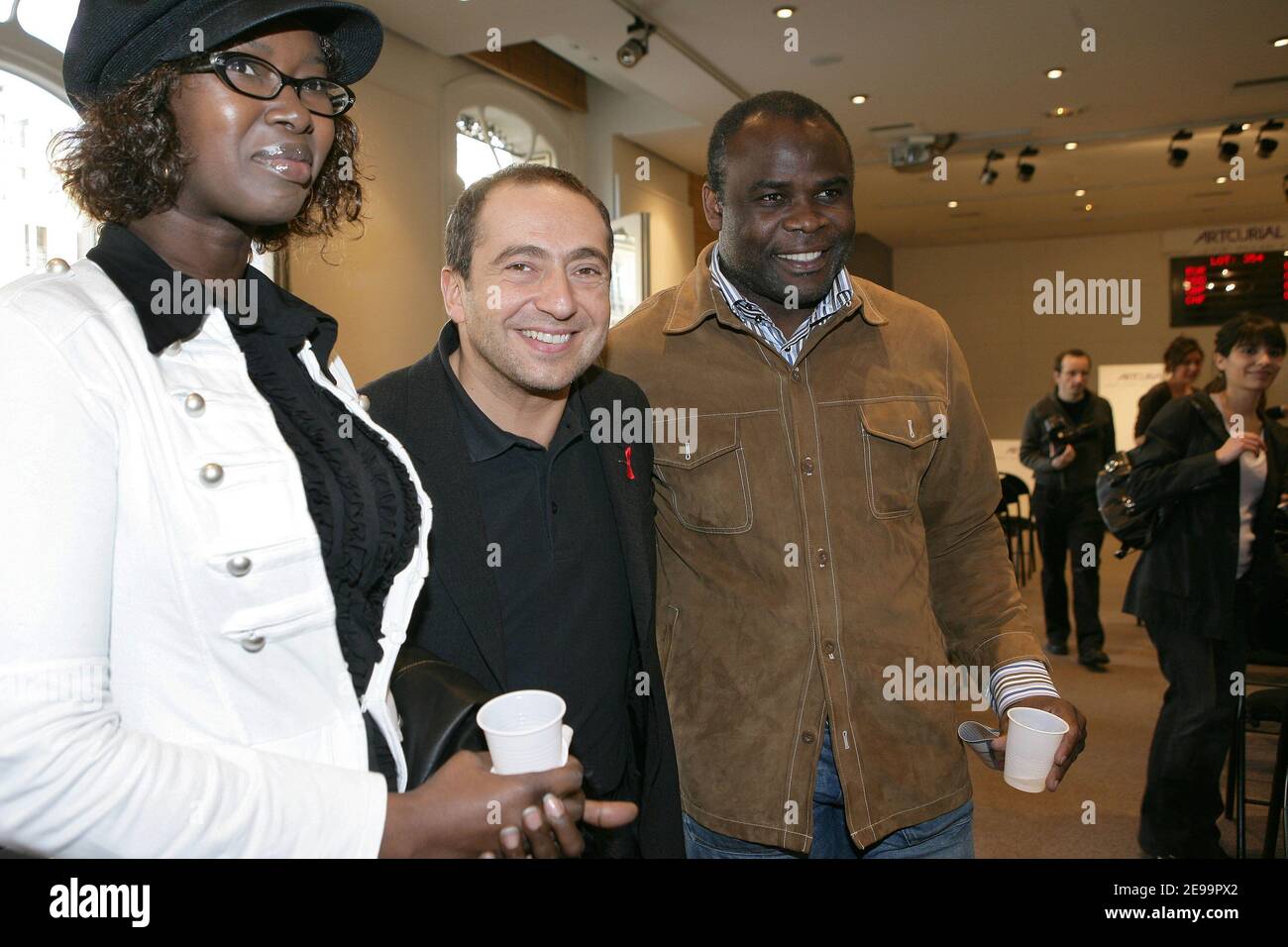 L to R) French soccer Basile Boli's wife, actor Patrick Timsit and soccer Basile  Boli attend an auction to sale personnalities paintings in aid of the  charitable organization 'Les Toiles de l'Espoir',