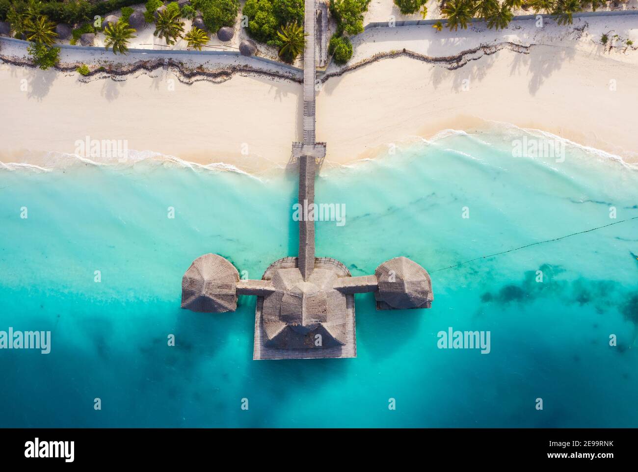 Aerial shot of the Stilt hut with palm thatch roof washed with turquoise Indian ocean waves on the white sand sandbank beach on Zanzibar island, Tanza Stock Photo