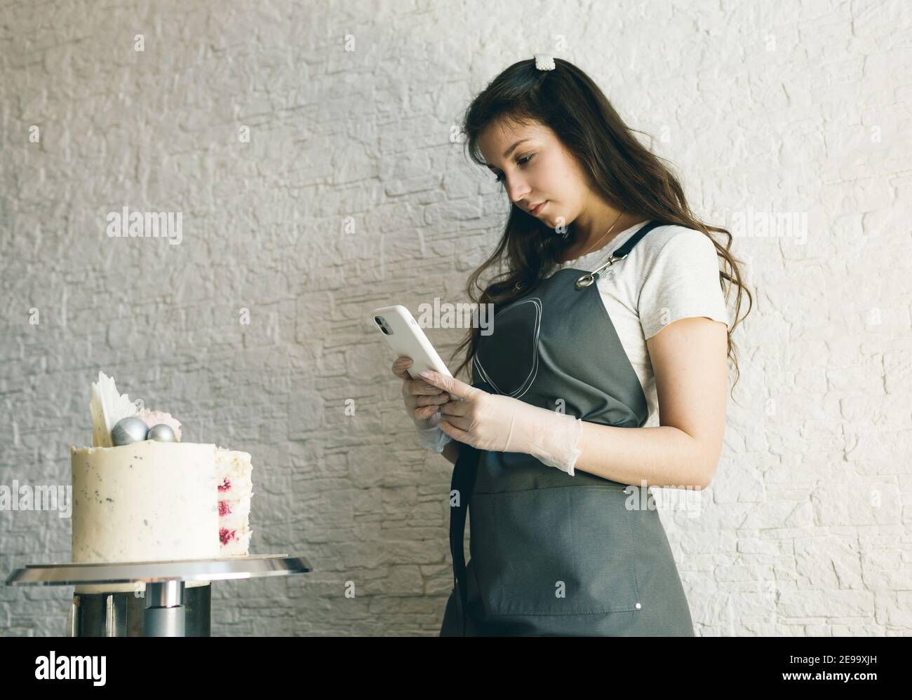 a young pastry chef girl takes pictures of a prepared cake Stock Photo