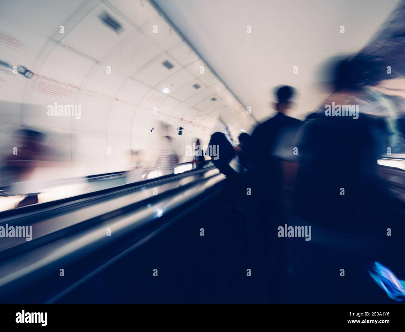 Blurred motion silhouettes of unrecognizable male with backpack inside Parisian underground metro moving escalator walkway taking the fastest route to interchanges with other lines Stock Photo