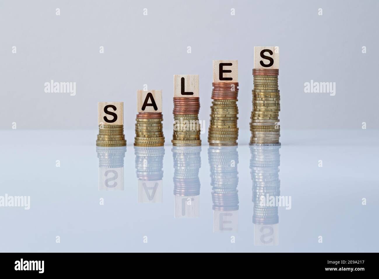 Word 'SALES' on wooden blocks on top of ascending stacks of coins on gray background. Concept of economy, business, finance, financial growth&success. Stock Photo