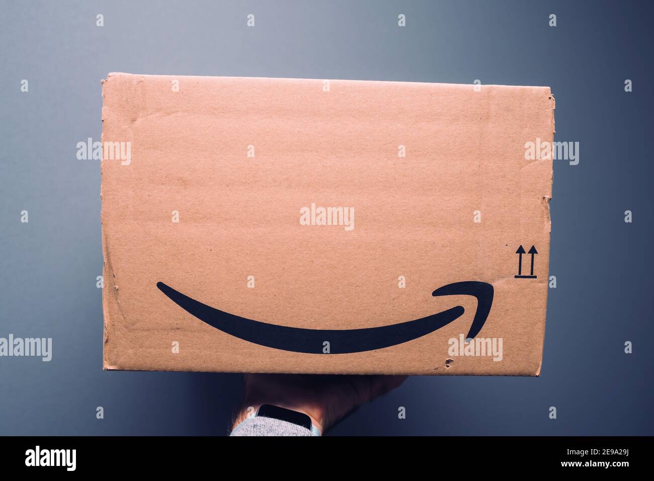 Paris, France - Oct 29, 2018: POV male hand holding new package of Amazon prime cardboard parcel delivered with the iconic smile-arrow symbol Stock Photo