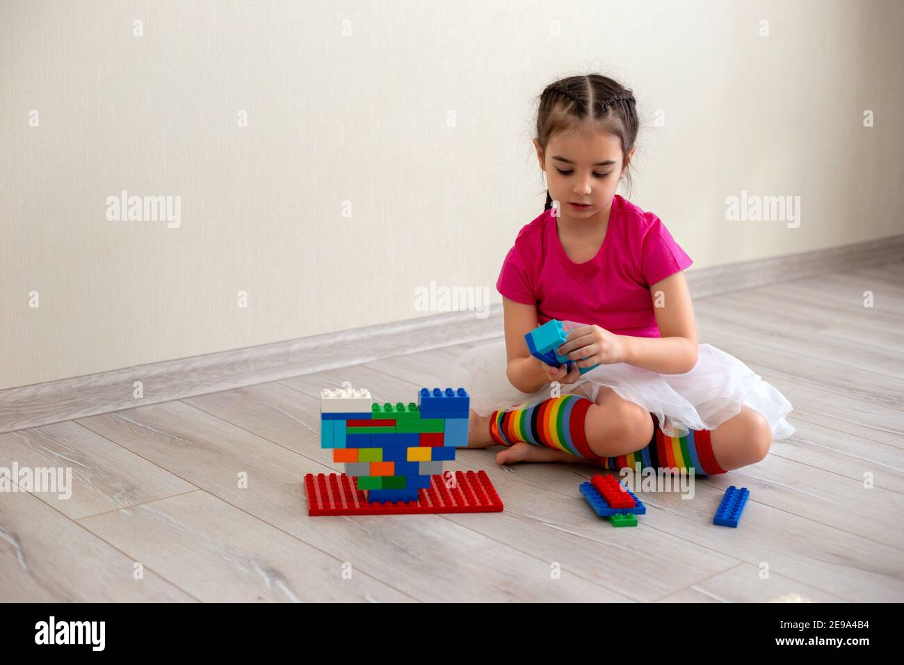 Girl play with multi-colored plastic constructor on floor Stock Photo