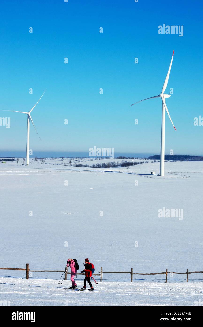 Two wind turbines winter mountain couple snow scenery people skiing Stock Photo