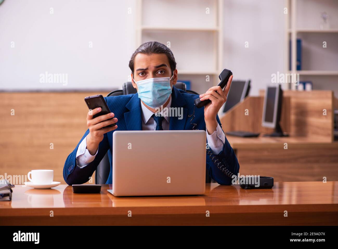 Young employee working in the office wearing mask Stock Photo - Alamy