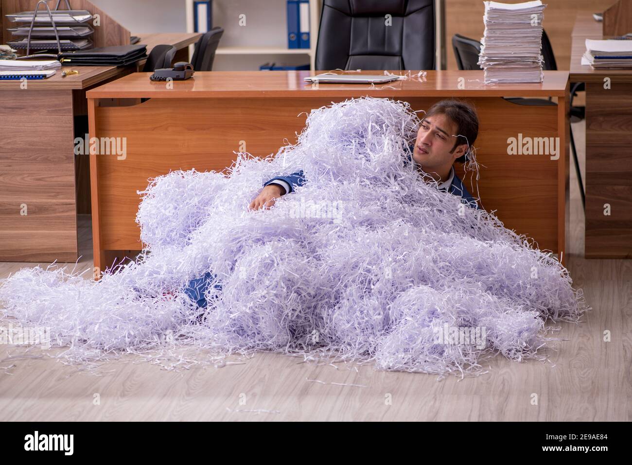 Young male employee cutting papers in the office Stock Photo - Alamy