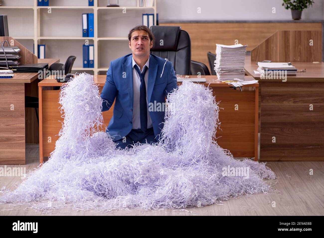 Young male employee cutting papers in the office Stock Photo - Alamy