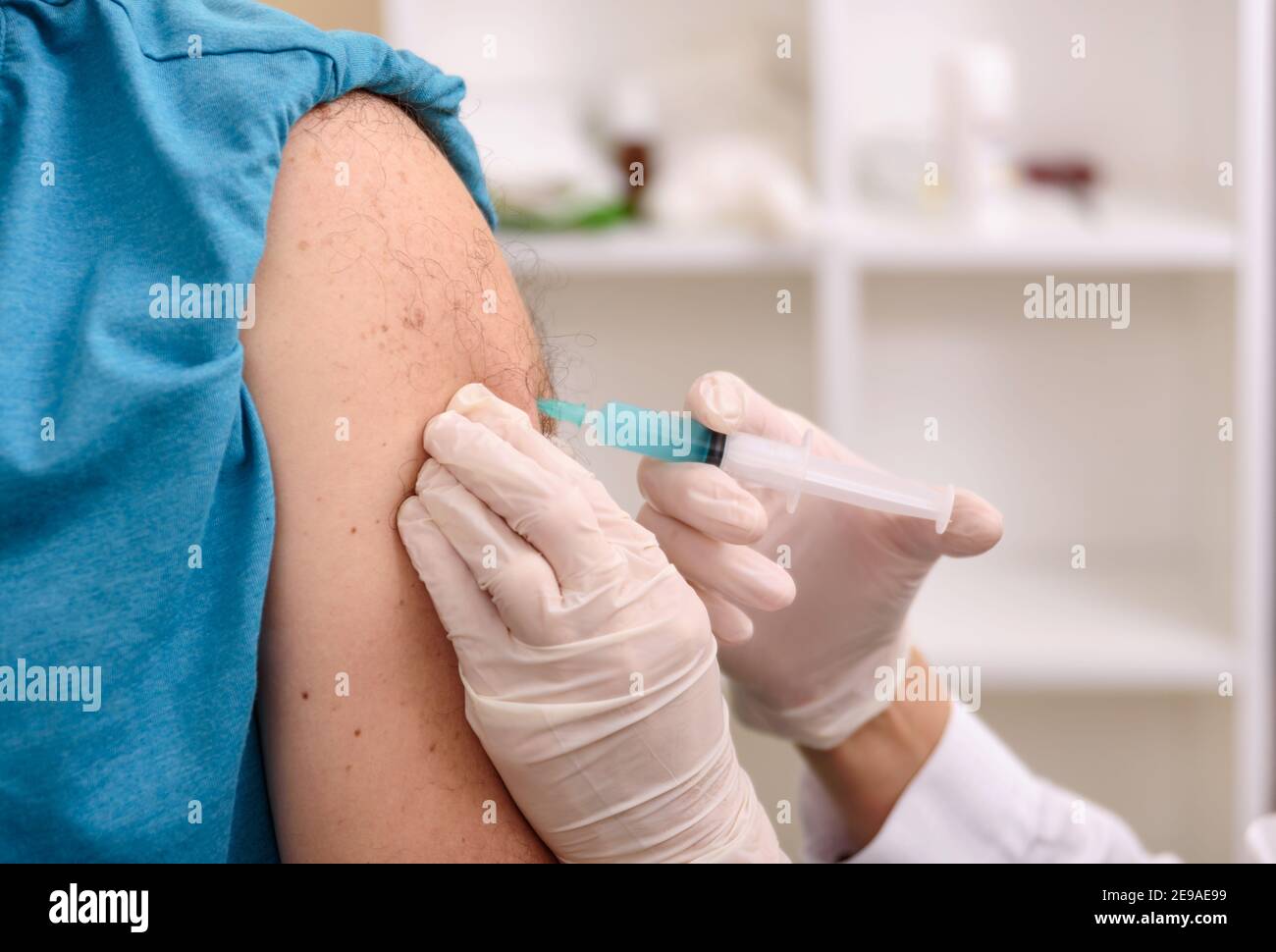 Hand of medical staff injecting coronavirus covid-19 vaccine in vaccine syringe to arm muscle Stock Photo