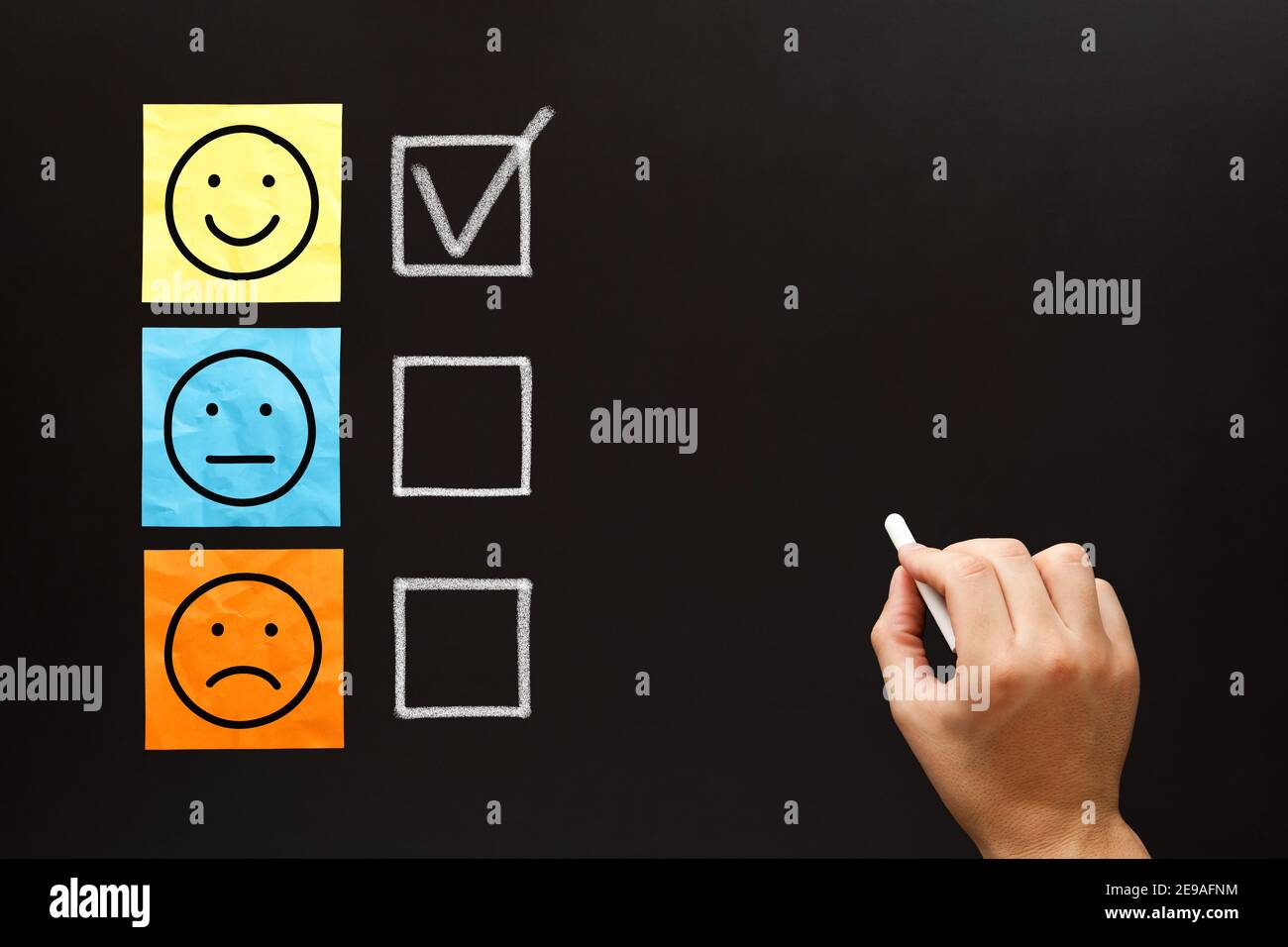 Happy client filling out a feedback survey with white chalk on blackboard. Customer satisfaction evaluation form concept. Stock Photo