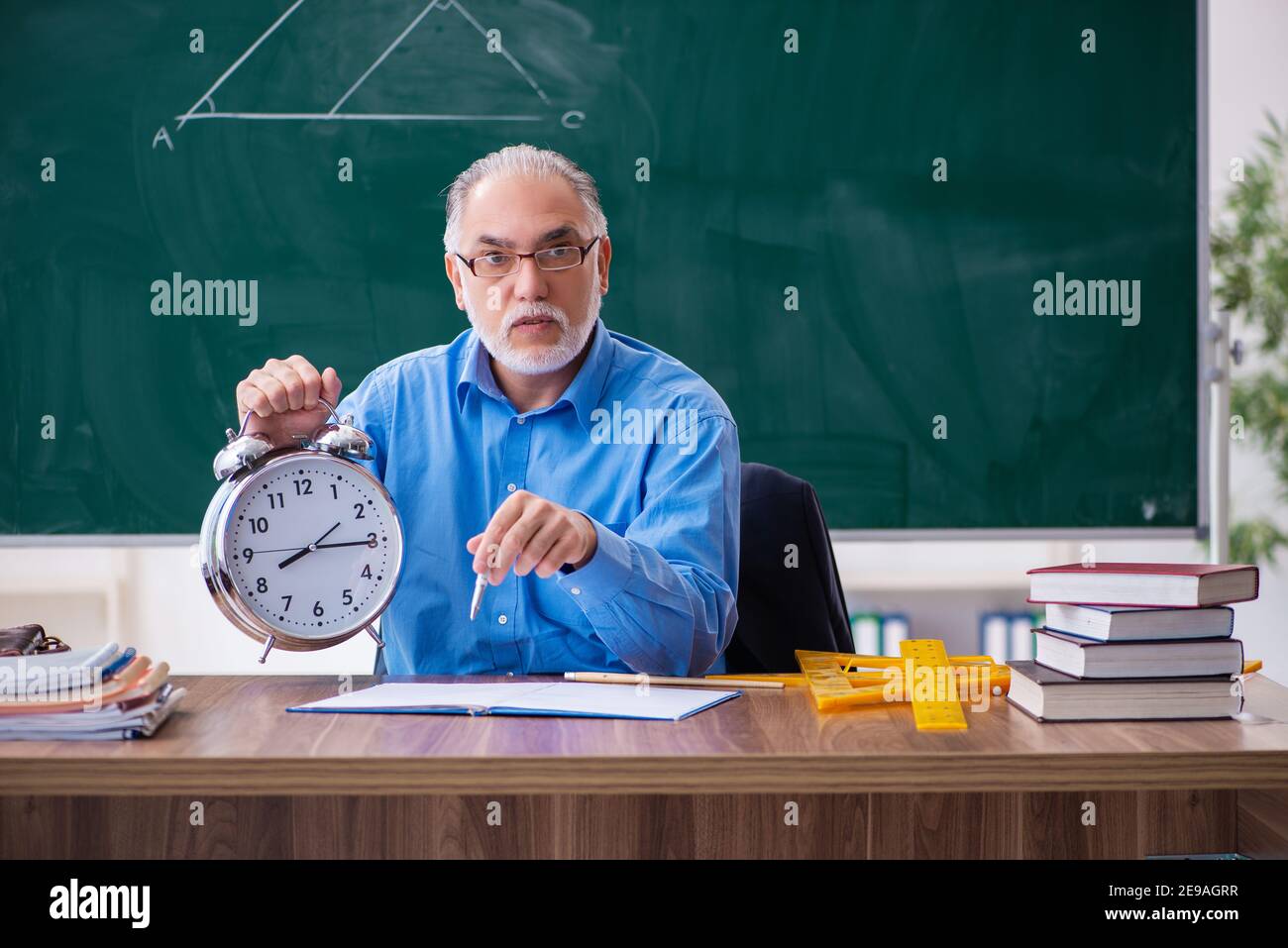 Senior male math teacher in time management concept Stock Photo - Alamy