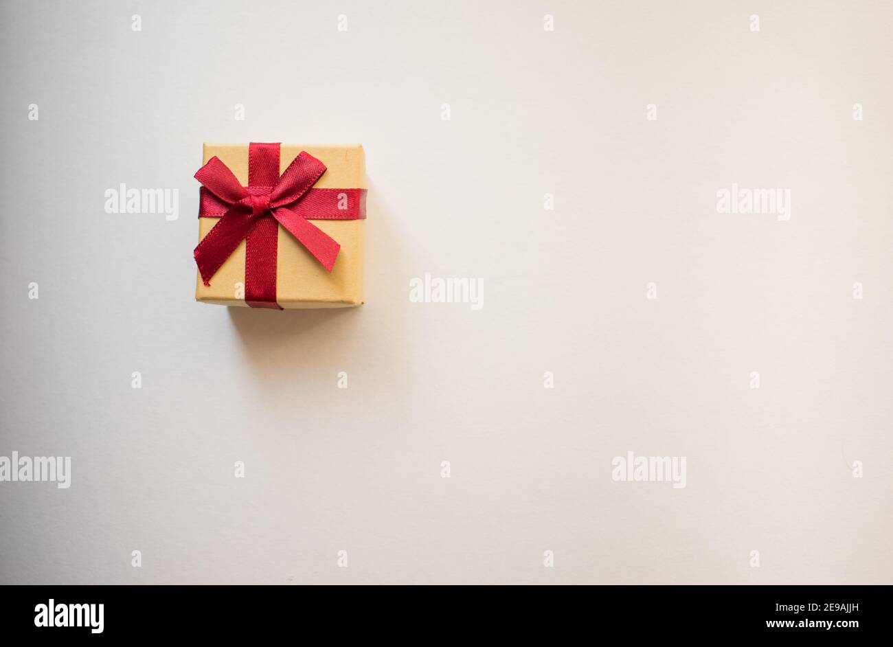 A small gift box with tied decorative bow and red ribbon on white ...