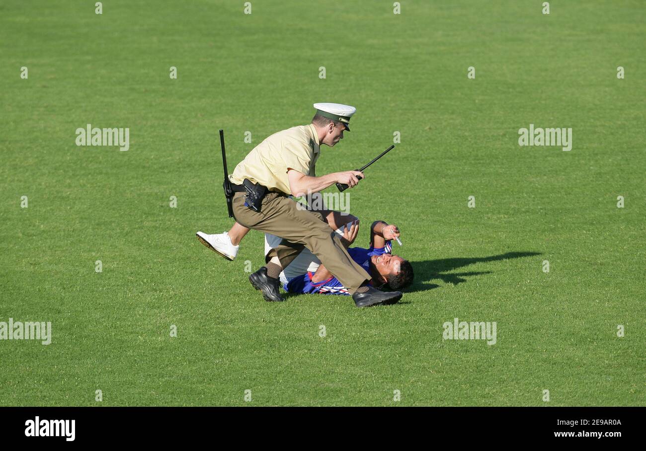 Two policemen stop a supporter as he runs onto the pitch during the  training session of France National Team at the Weserbergland Stadium on  June 10, 2006 in Hameln, Germany. Photo by