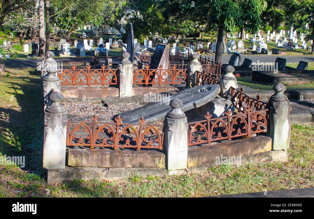 Deteriorated grave with fallen tombstone and rusty perimeter fence in Toowong cemetary near Brisbane Queensland Australia 8 23 2015 Stock Photo