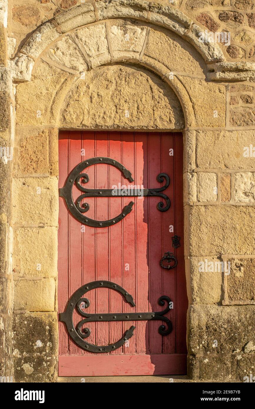 Ancien red wooden door with black ironwork in a stone wall Stock Photo ...