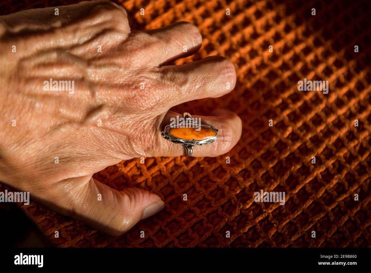 Female hand gripping an orange ring on an orange cover Stock Photo