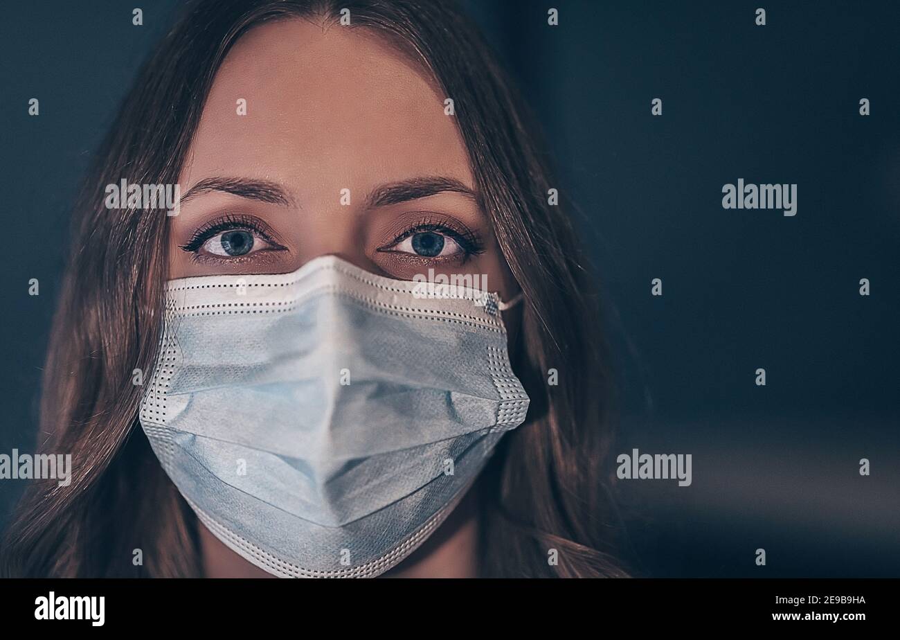 Young woman wearing medical face mask to prevent others from corona COVID-19 and SARS cov 2 infection. Portrait of a young woman wearing a blue face m Stock Photo