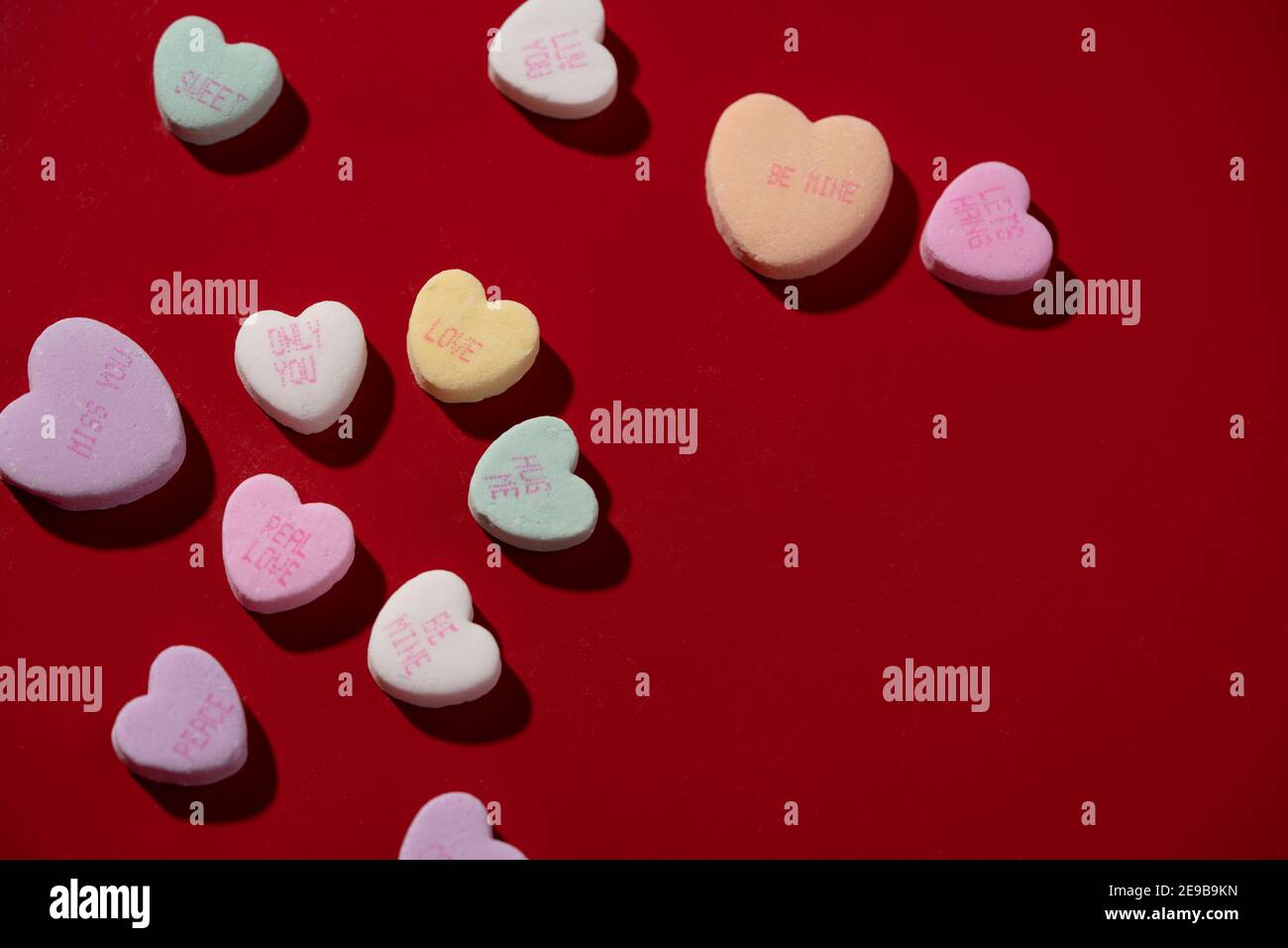 Colorful conversation candy hearts arranged on a red surface. Stock Photo