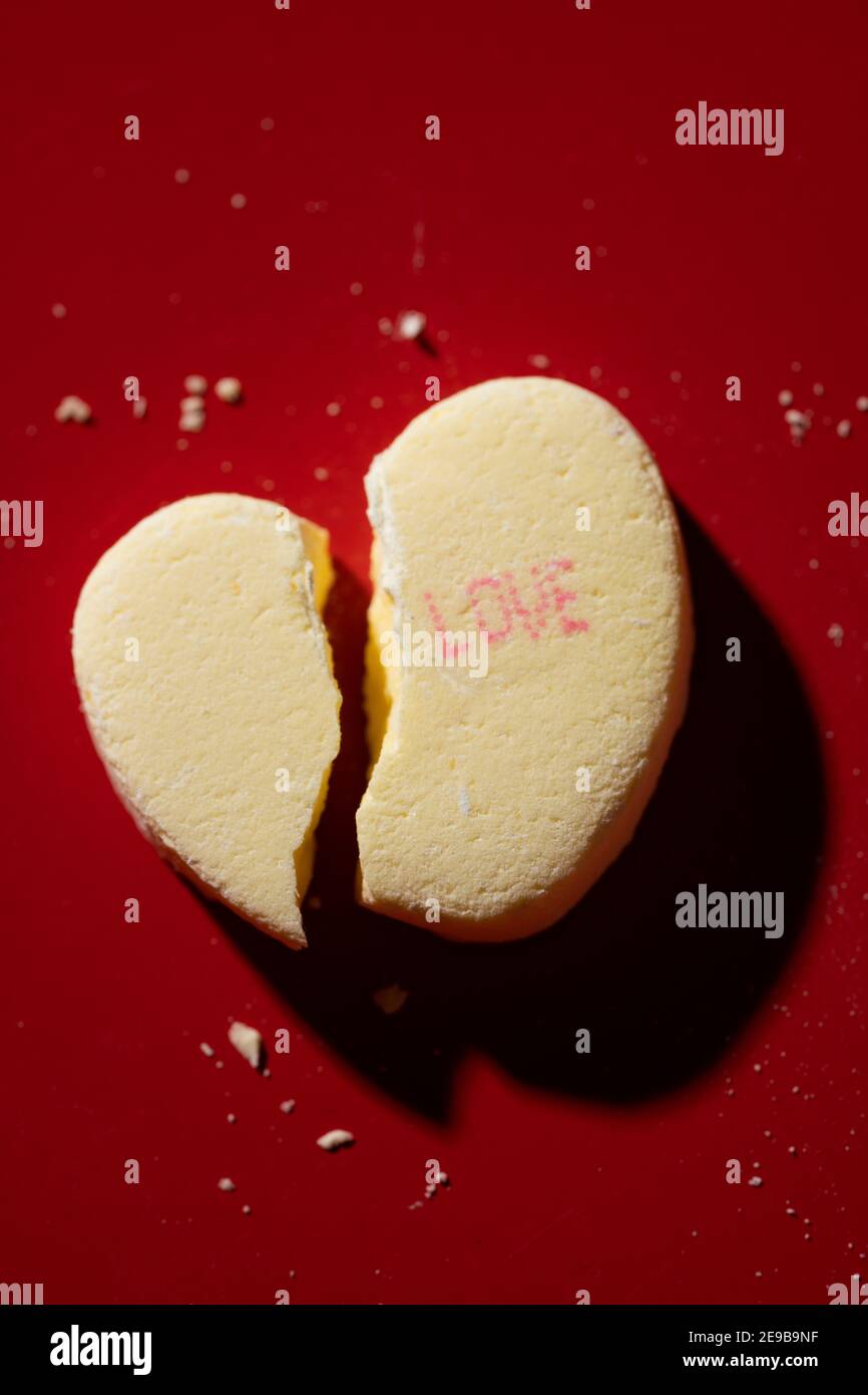 A broken candy conversation heart with 'Love' printed on it Stock Photo