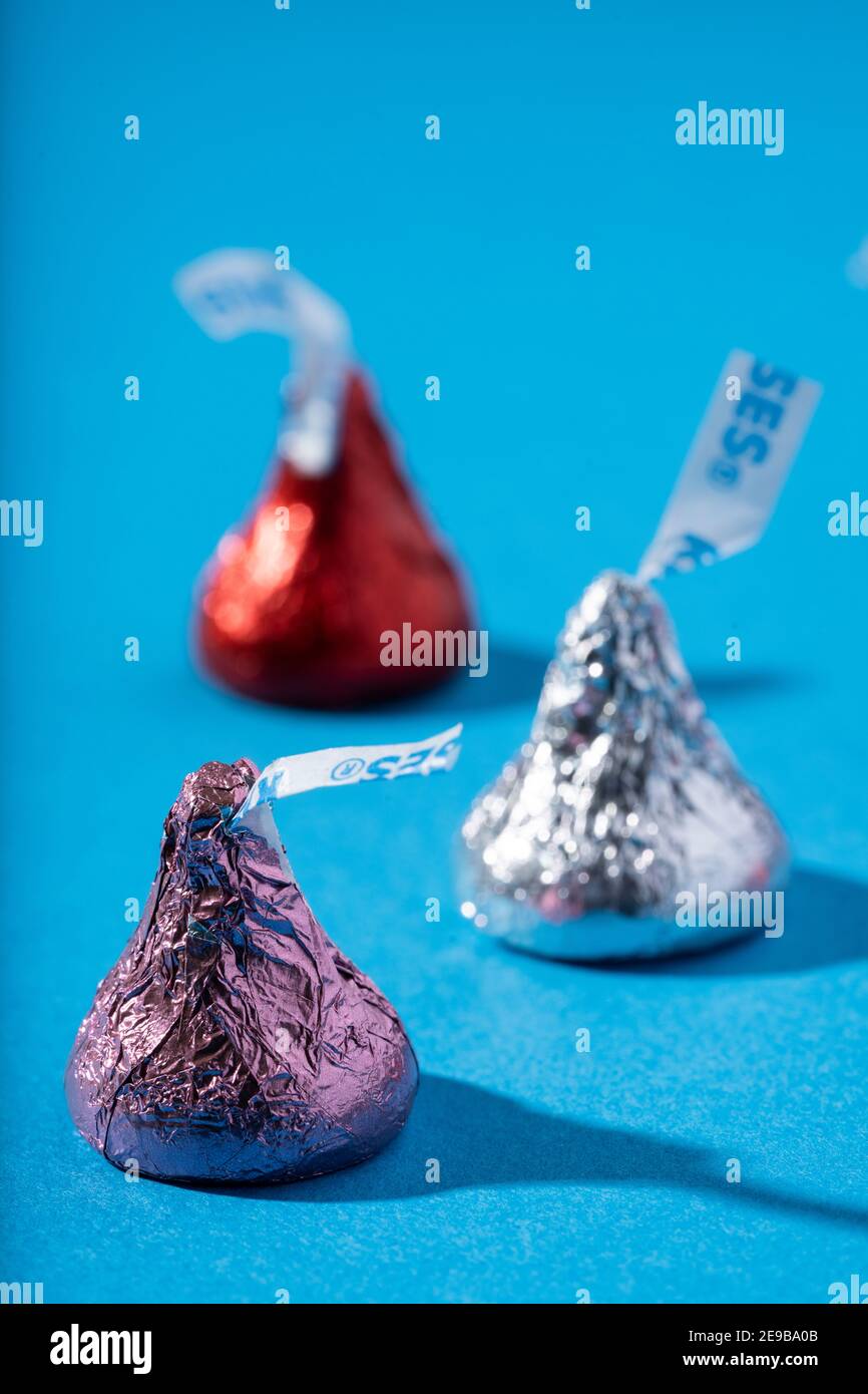 Three wrapped Hershey Kisses on a blue surface Stock Photo