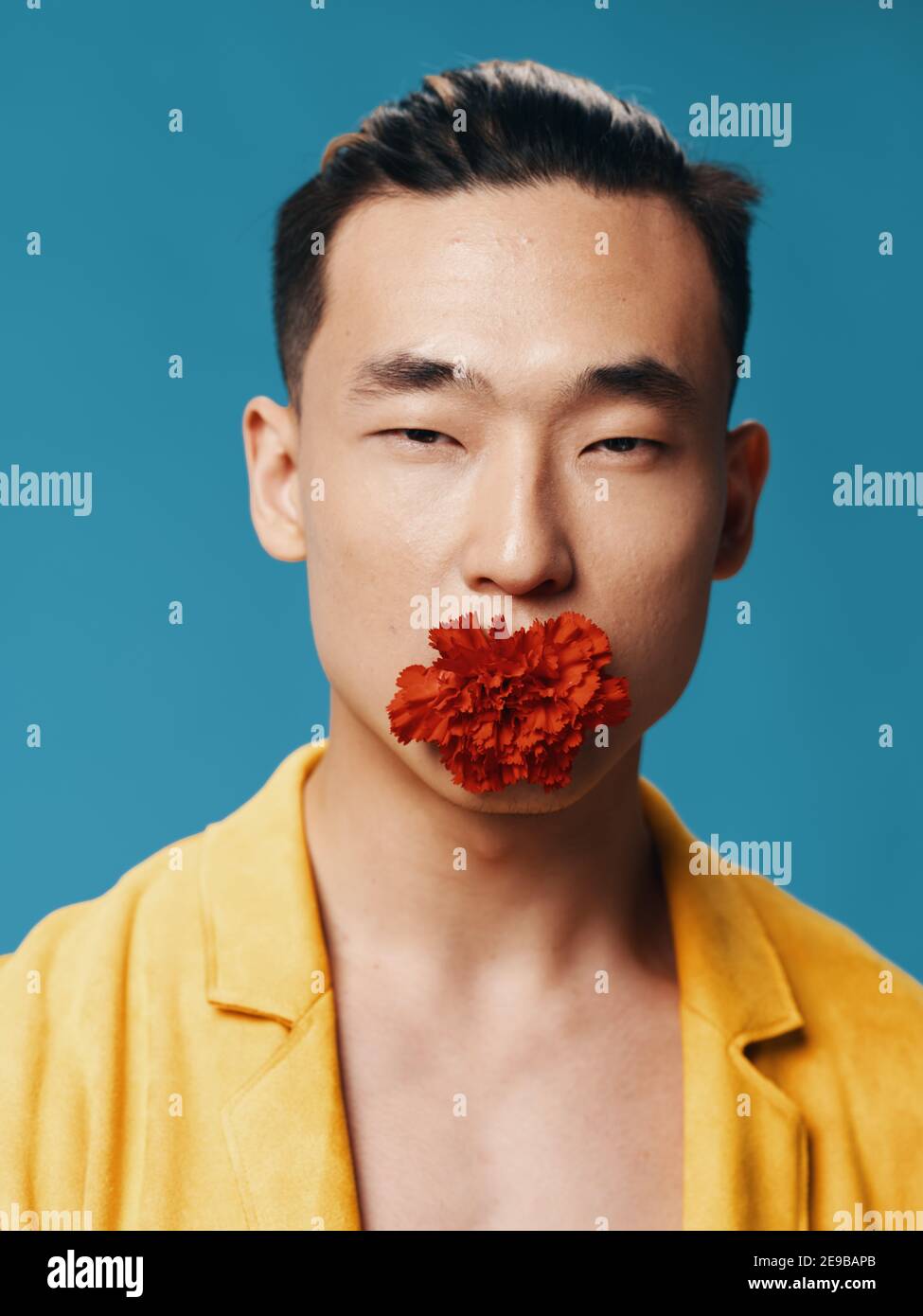 Korean male with narrow eyes yellow jacket and red flower in his mouth Stock Photo Alamy
