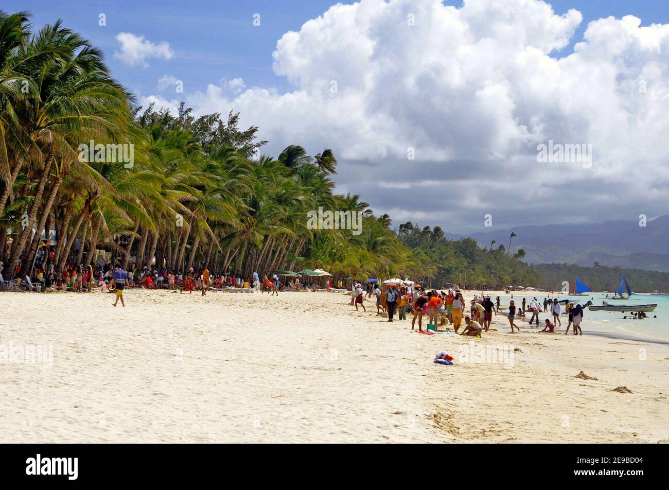 Tourists enjoy White Beach on the tropical island of Boracay in the Western Visayas of the Philippines.  Taken in 2005, the issue of carrying capacity and tourism impacts were starting to appear.  Thirteen years later, in 2018, the entire island was closed by the government so that it could be rehabilitated and redeveloped in a more sustainable way.  The six month closure was followed by a slow phased in opening thereafter. Stock Photo