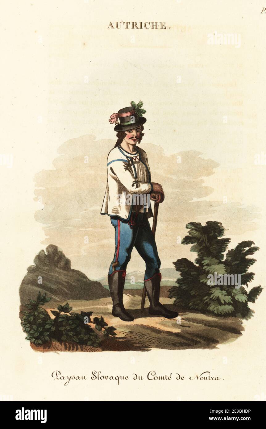Slav youth of Nitra Country, Kingdom of Hungary (Slovakia), 18th century. He wears a holiday dress, hat decked with ribbons, embroidered jacket, blue pantaloons, Hungarian half-boots with a tobacco pipe in the right one. Schlavonian man of the County of Neutra, Paysan Slovaque du Comte de Neutra. Handcoloured copperplate engraving after an illustration by William Alexander from J-B. Eyries’ L'Autriche: Costumes, Moeurs et Usages des Autrichiens, Austria: Costumes, Manners and Mores of the Austrians, Librairie de Gide Fils, Paris, 1823. Jean-Baptiste Eyries (1767-1846) was a French geographer, Stock Photo