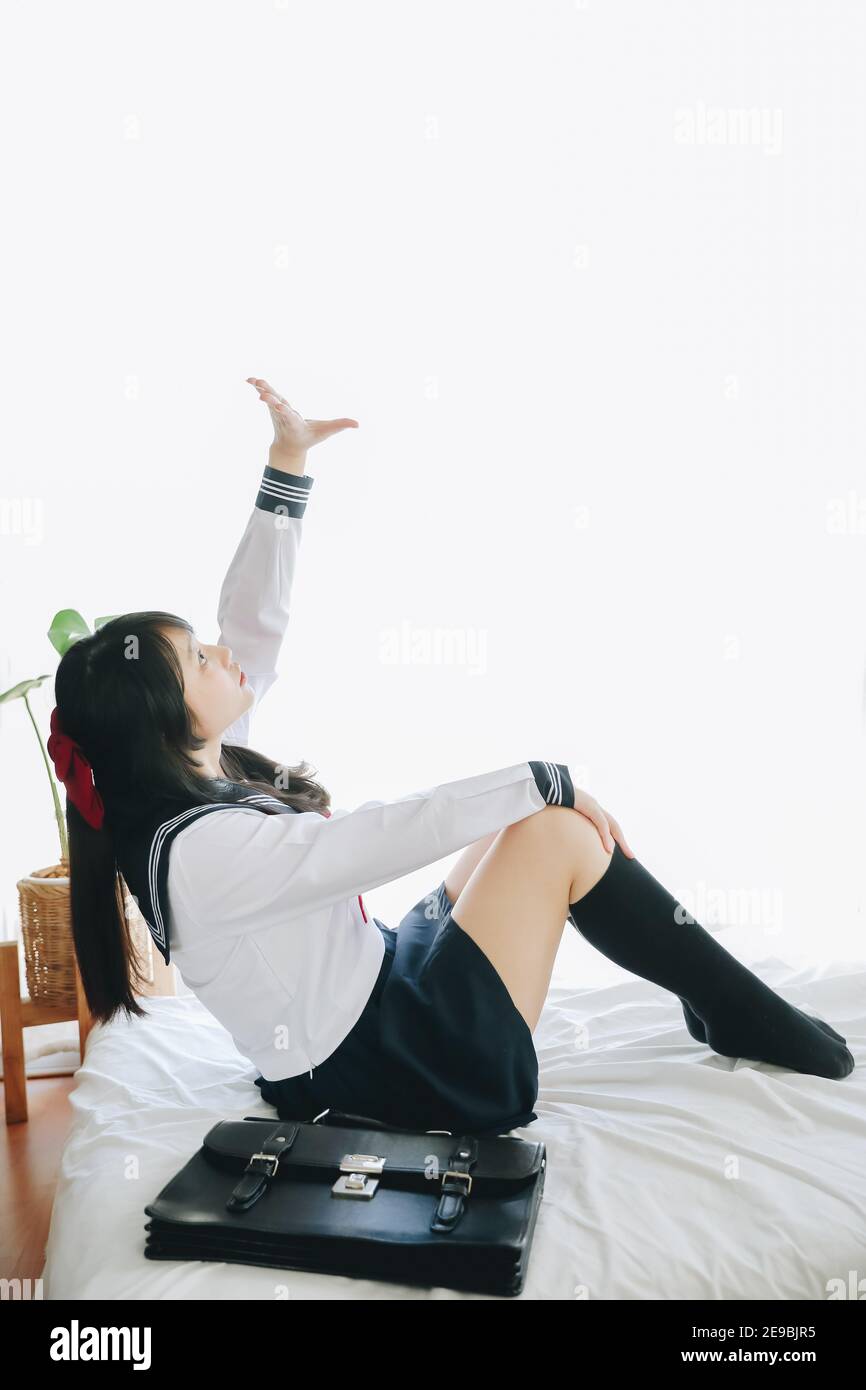 japanese school girl sitting on bedroom in white tone Stock Photo