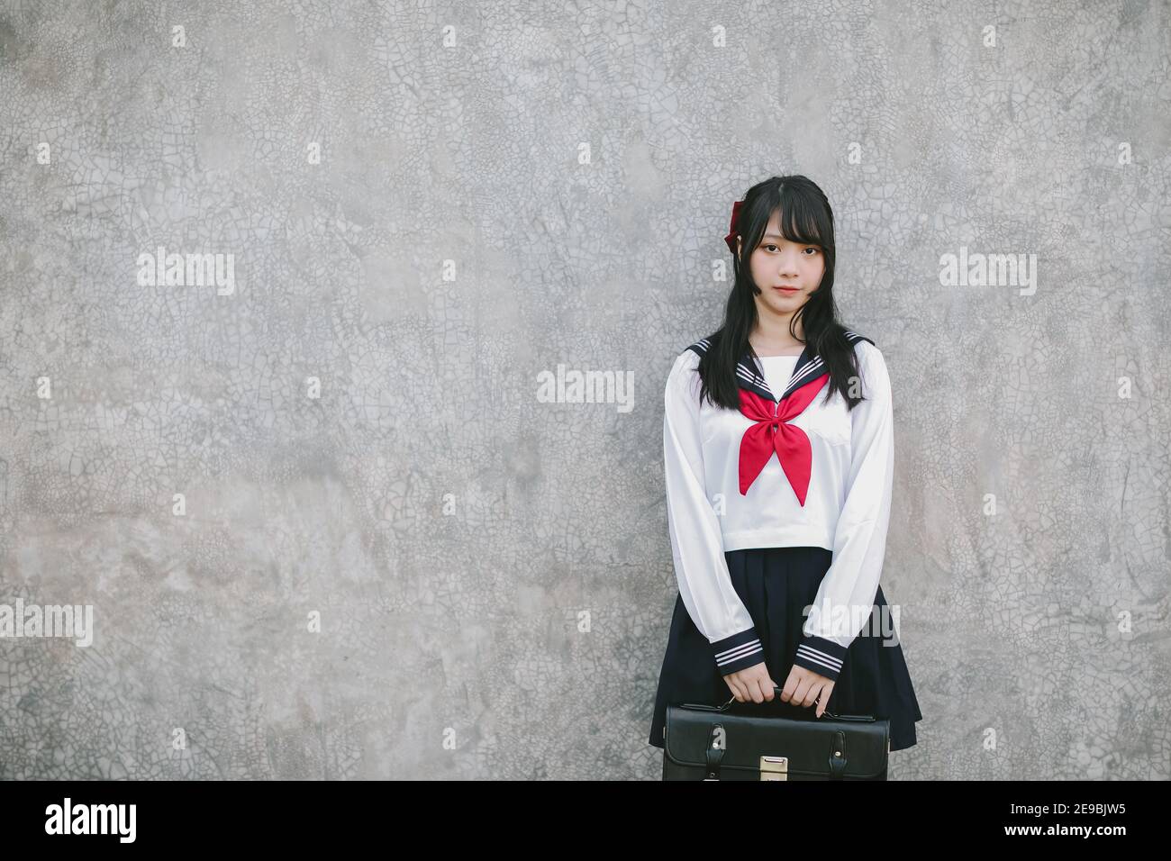 Portrait of Asian schoolgirl with grey background Stock Photo