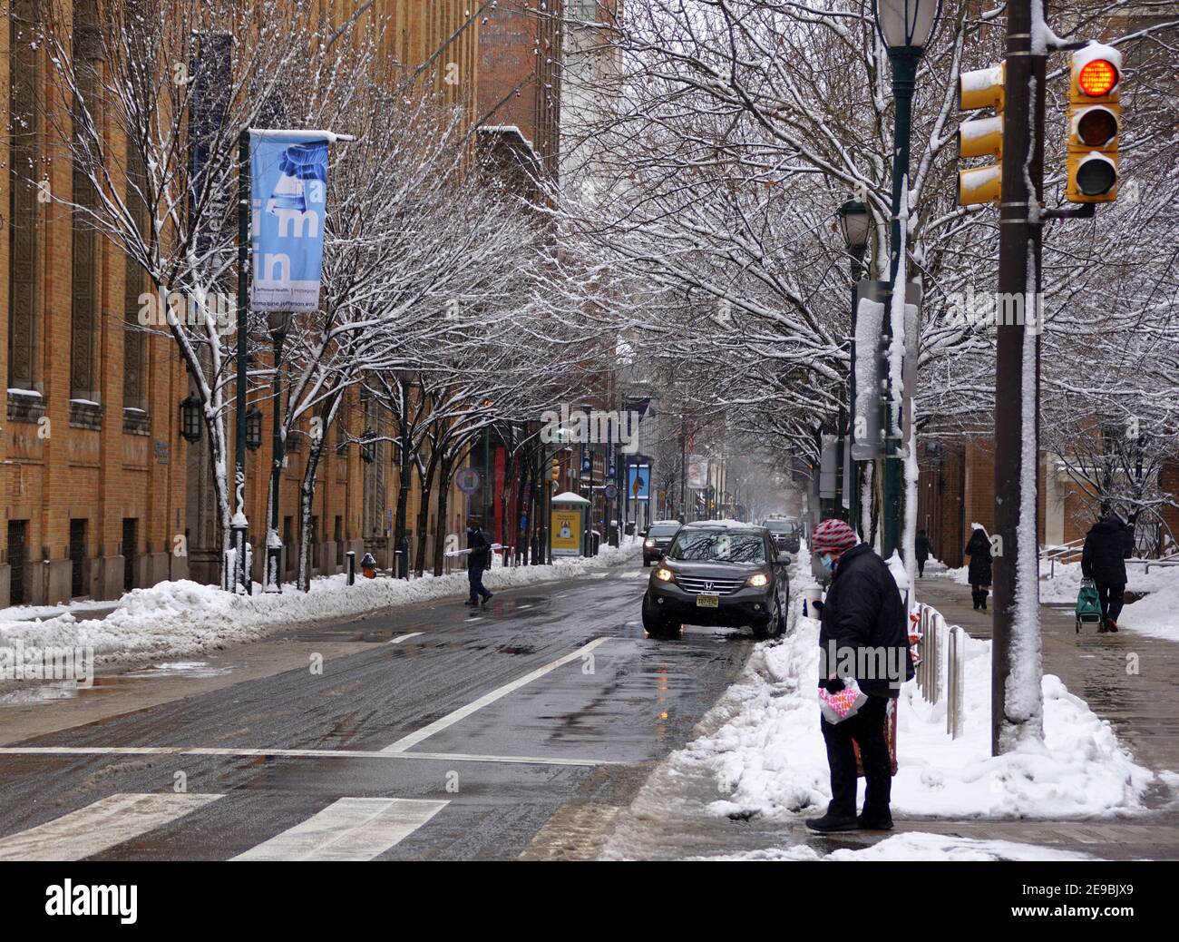 Philadelphia, Pennsylvania, U.S.A - February 2, 2021 - The traffic and people walking on the slippery and icy road after a snowstorm in the city Stock Photo