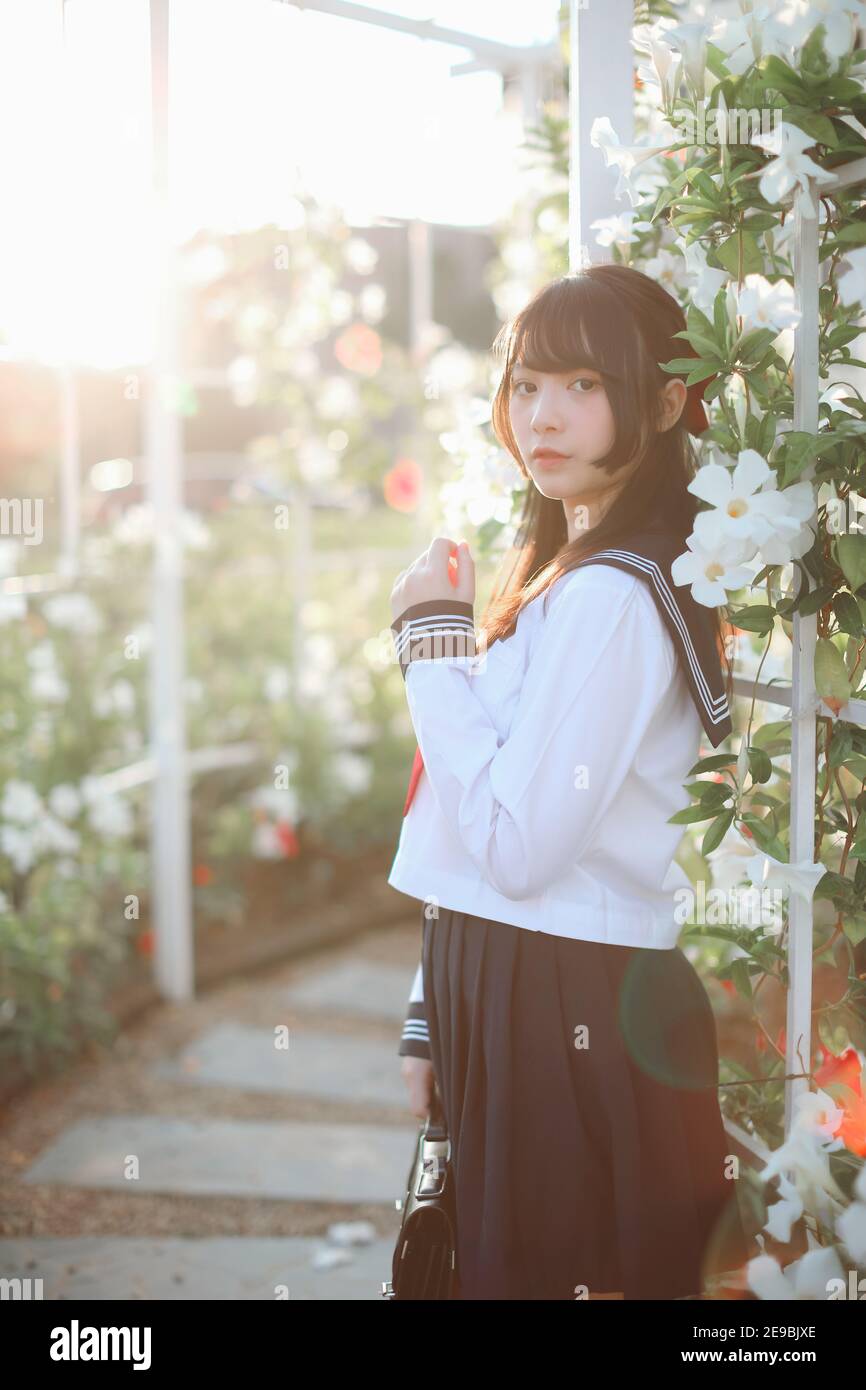 Asian school girl walk and looking with flower garden background Stock Photo