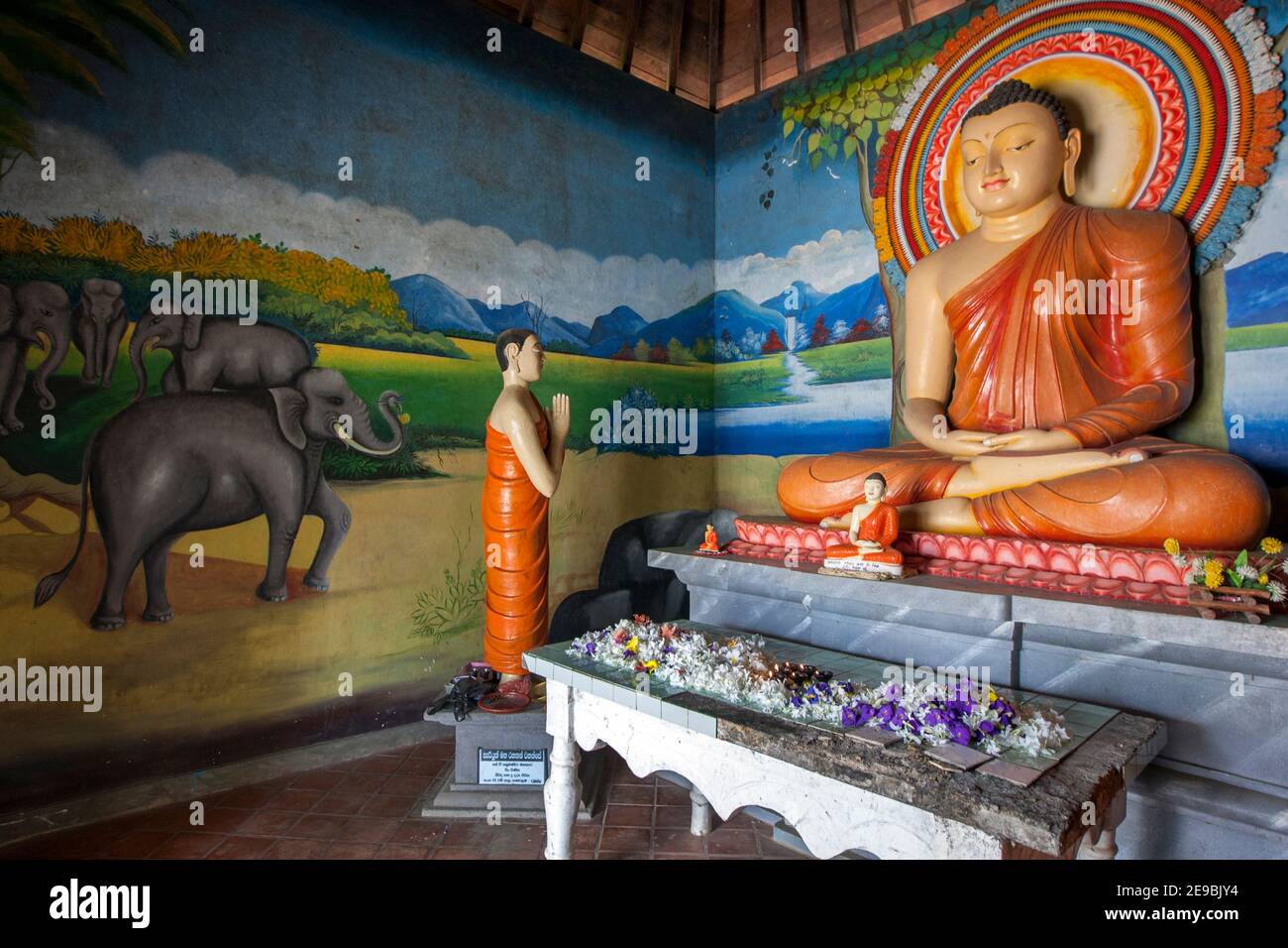 The colourful interior of the image house at the Sigiriya Buddhist Temple at Sigiriya in central Sri Lanka. The interior is dominated by a seated Budd Stock Photo