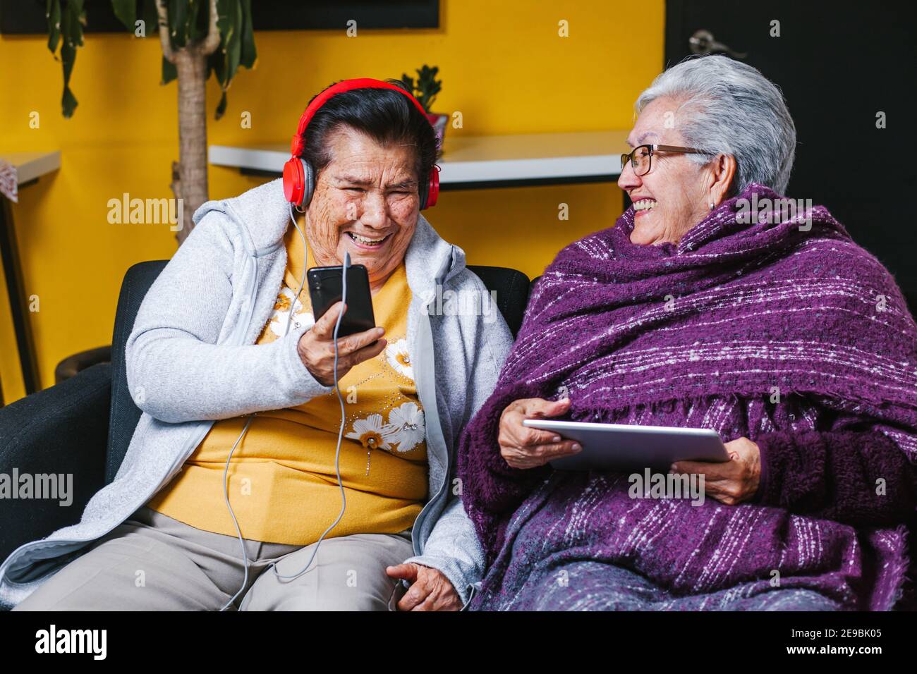 Latin Senior women listening music with headphones at home in Mexico