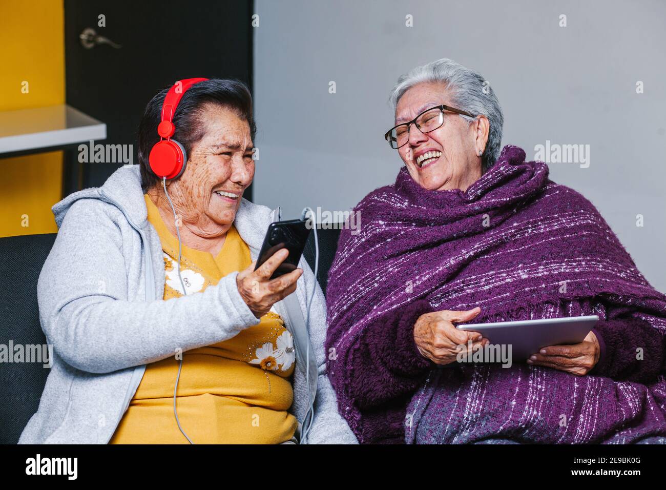 Latin Senior women listening music with headphones at home in Mexico