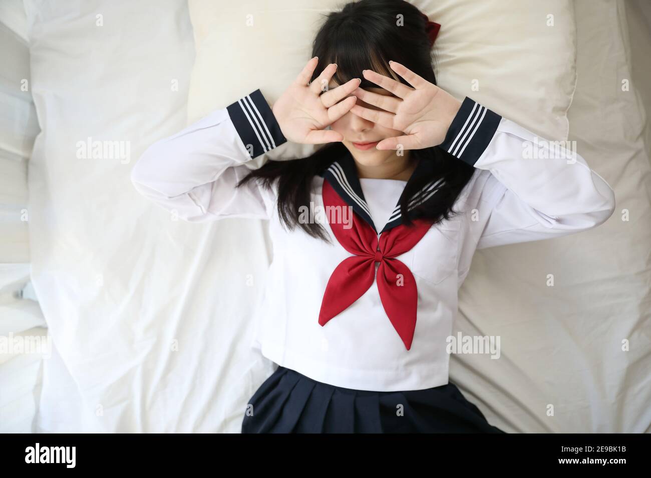 Portrait japanese school girl sleeping with pillow in white tone bed room Stock Photo