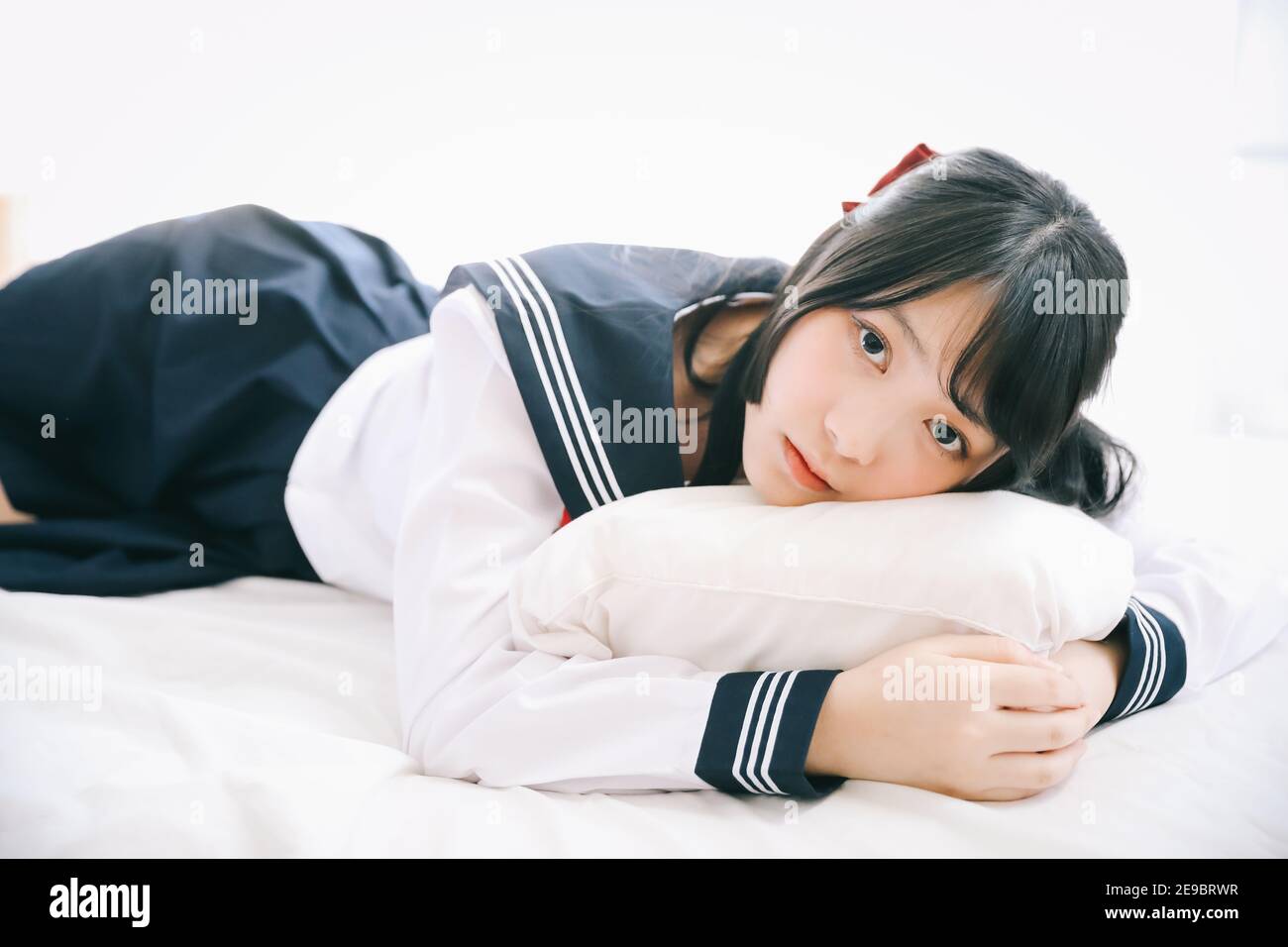 Portrait japanese school girl sleeping with pillow in white tone bed