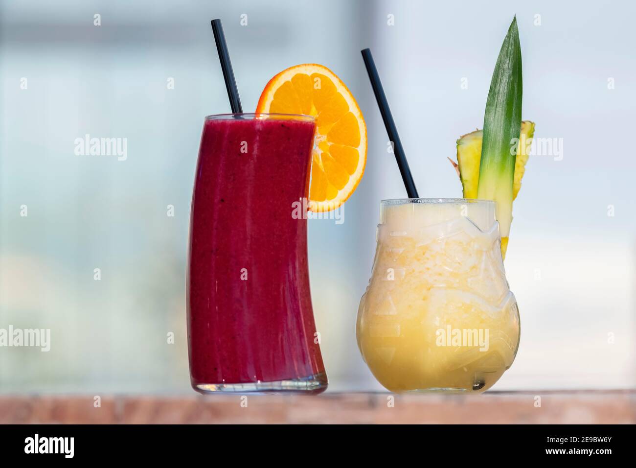 Freshly made cocktails with fruit pieces and black straws on a wooden table. Selective focus and close up. Leisure and lifestyle concept. Stock Photo