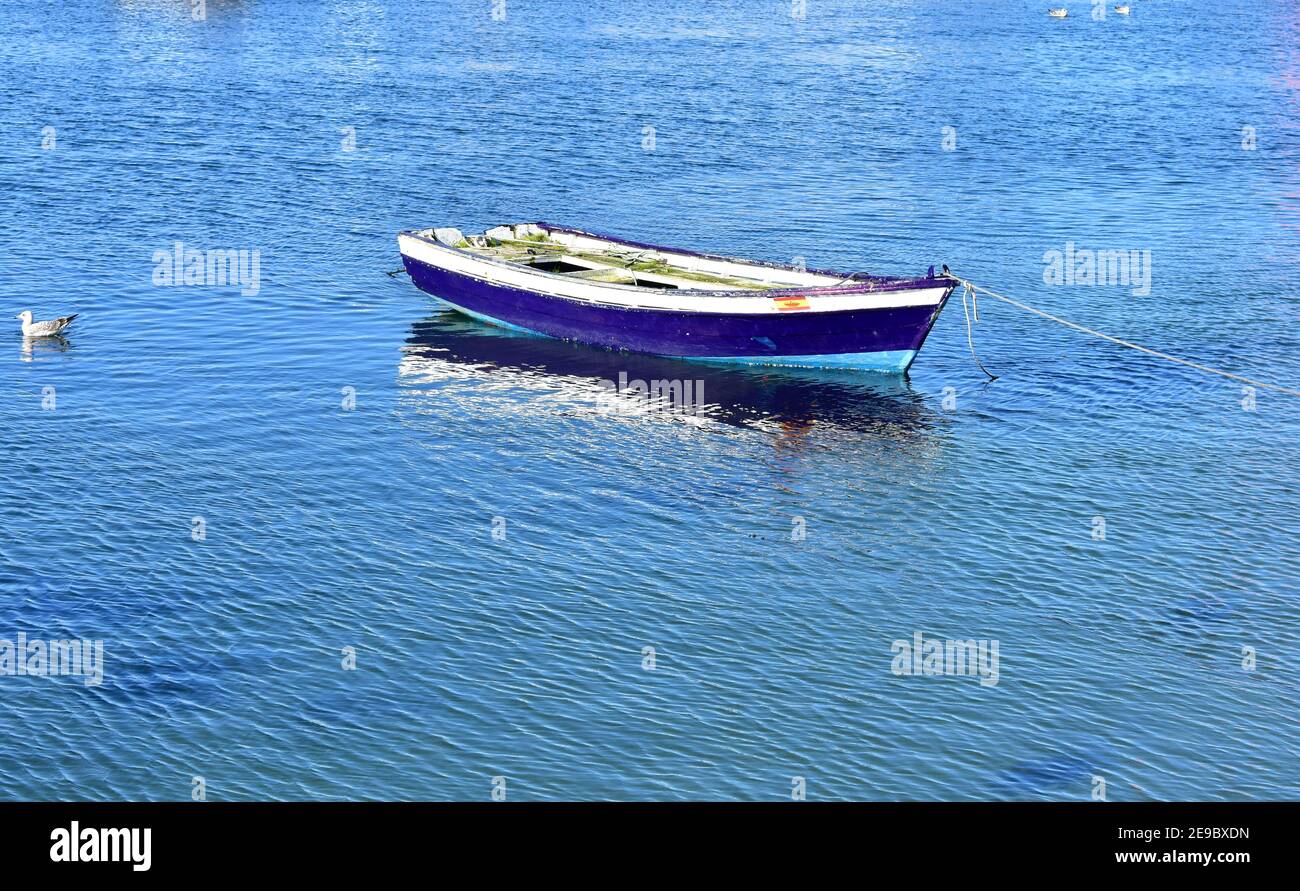Old blue wooden small boat floating on the sea at famous Rias Baixas in Galicia Region. Spain. Stock Photo