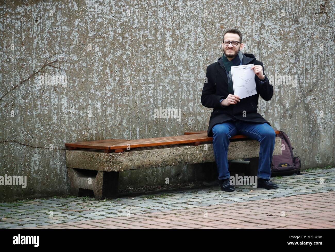 Syrian Abdul Kader Tizini who graduated with a master's degree in mechanical  engineering from RWTH Aachen, holds a copy of his master certificate as he  sits on a bench at the campus