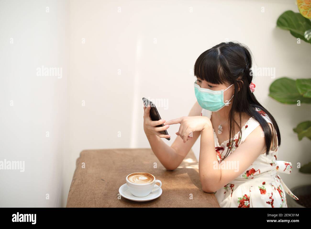 Portrait Female with mask using smartphone in coffee shop on covid-19 virus outbreak , Business concept Stock Photo