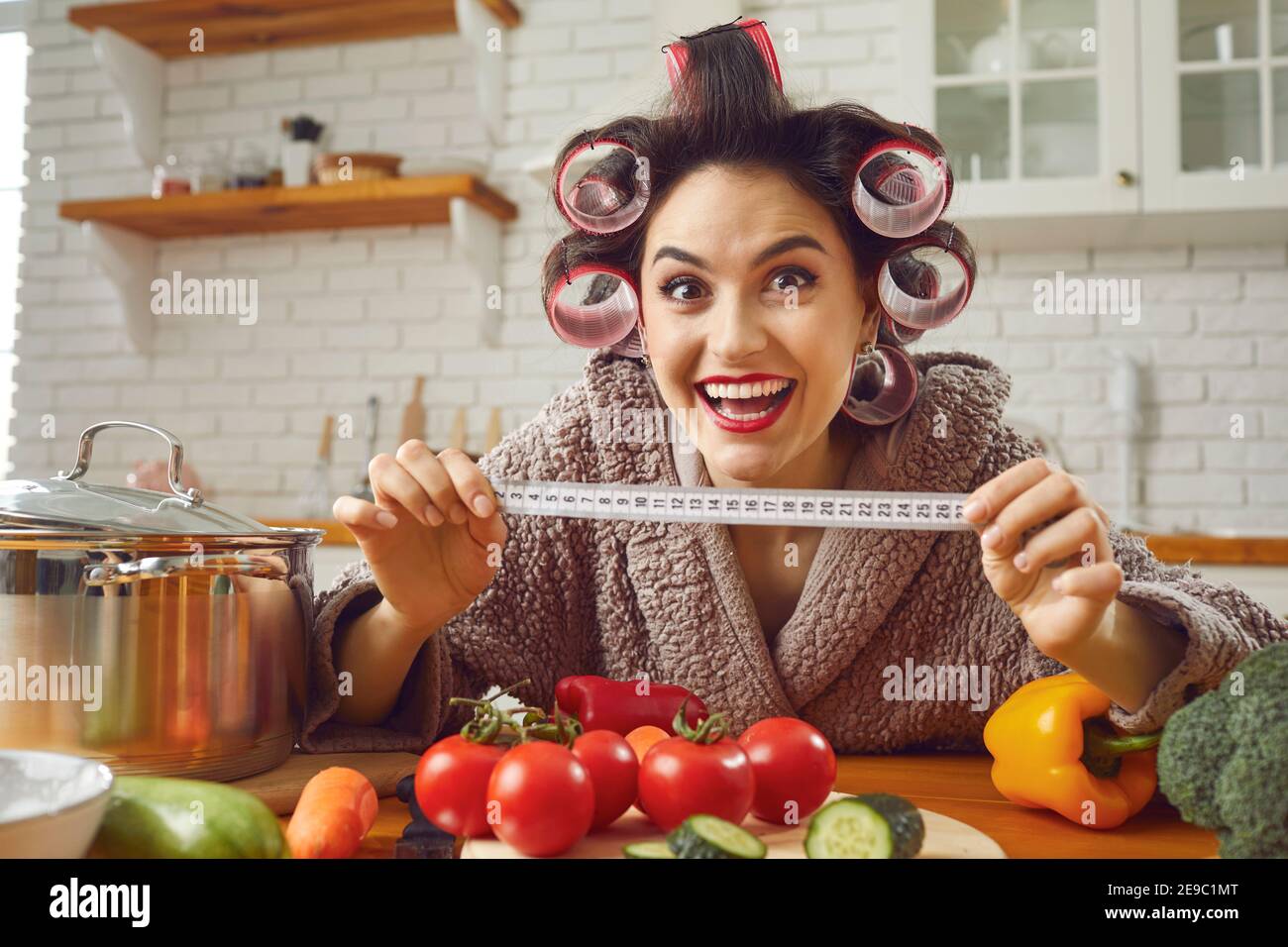 Funny housewife holding a tape measure and showing how much weight she has lost on a diet Stock Photo