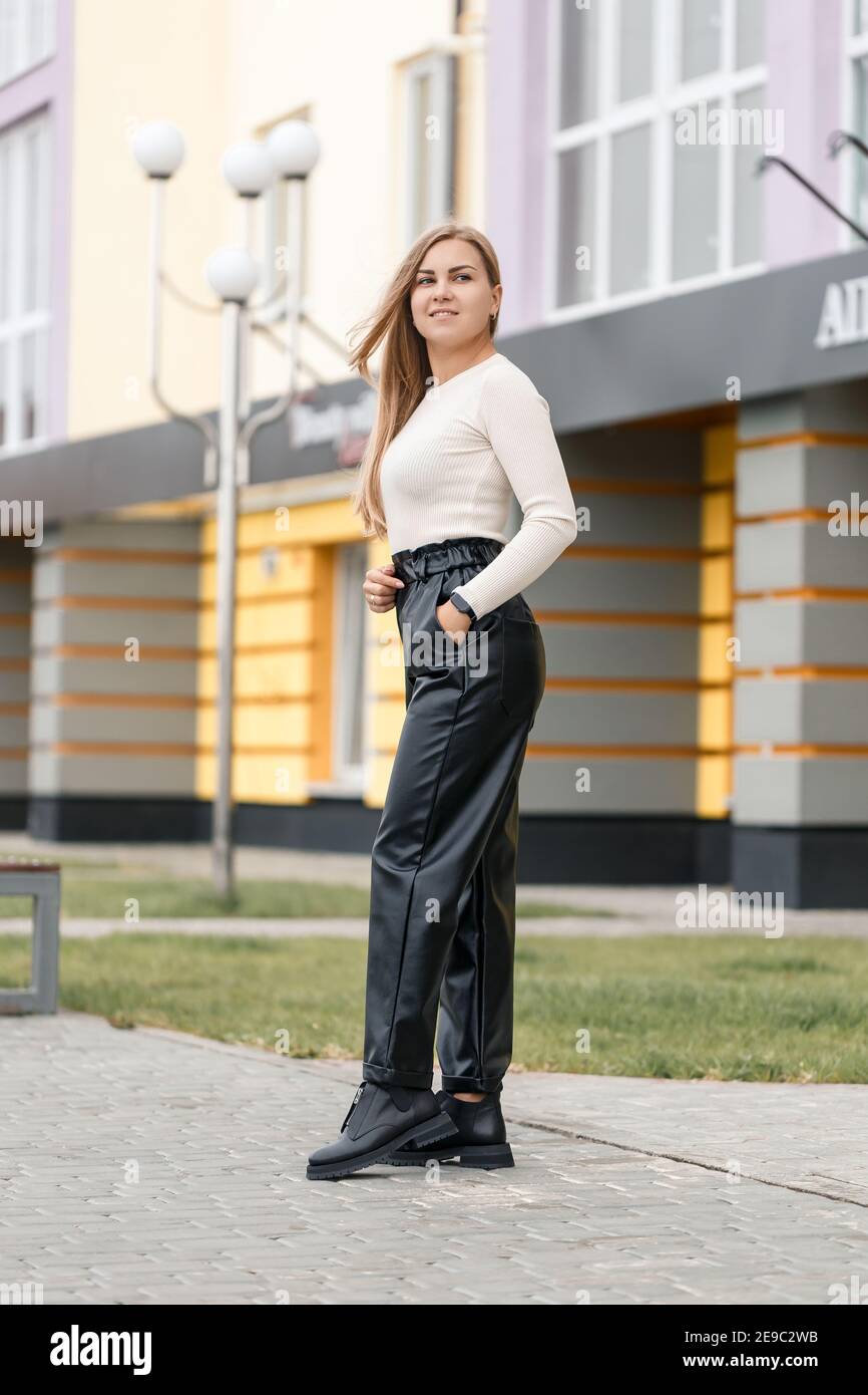Young woman in black leather pants on the street. Womens Trendy