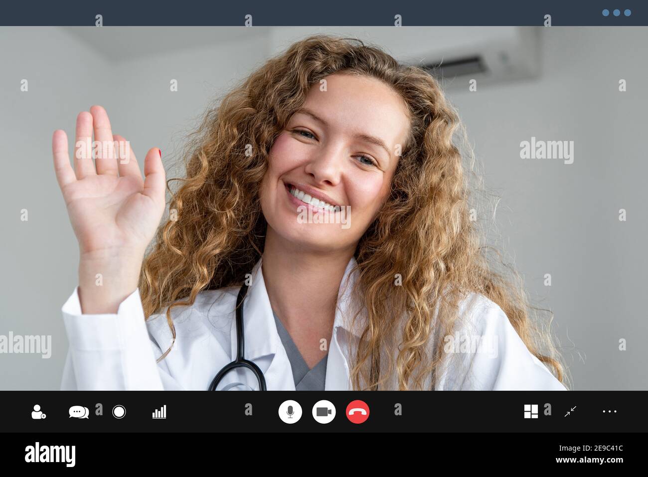 Young female doctor waving hand greeting patient online via video call, home medical consulation service concepts Stock Photo