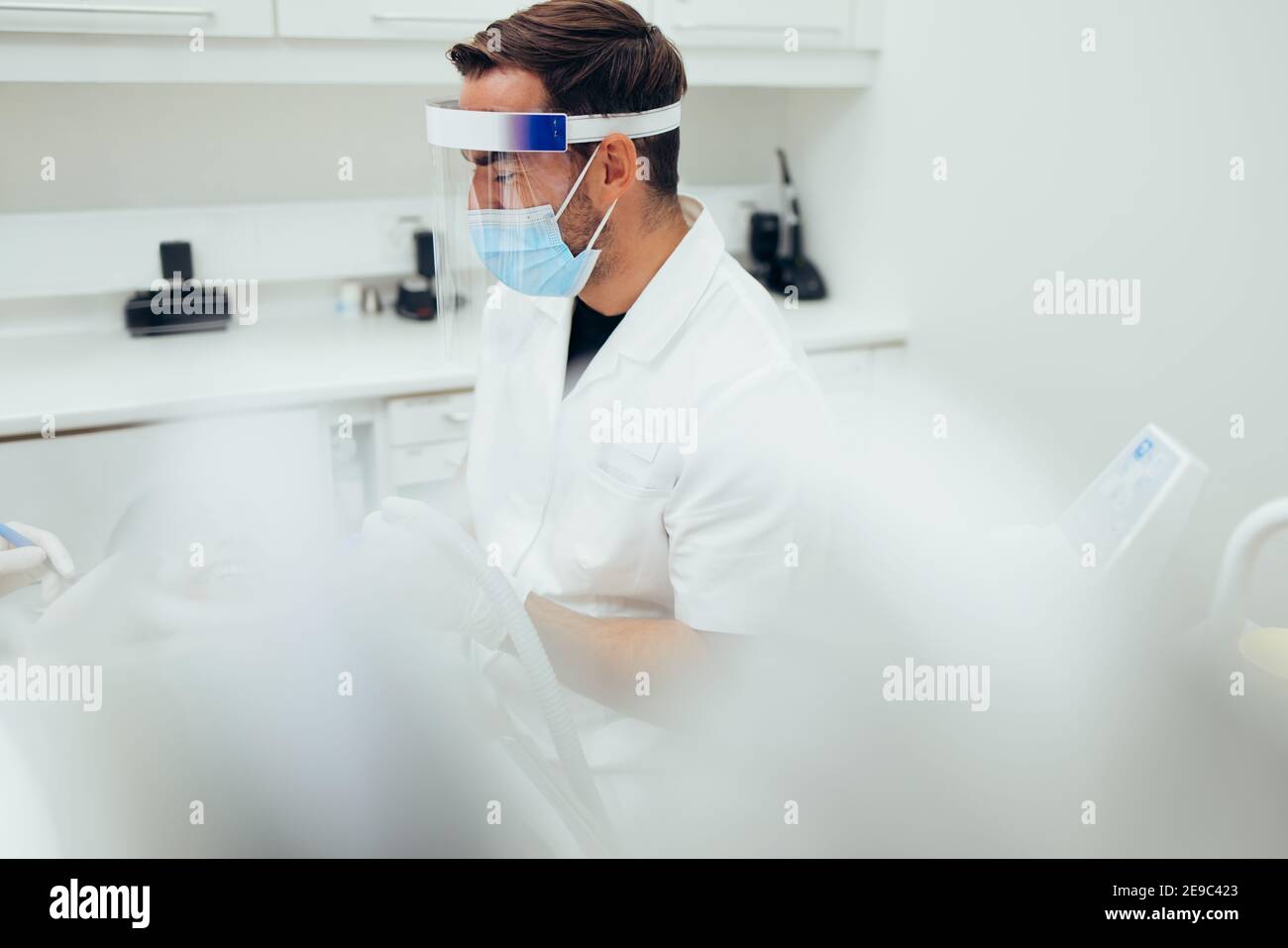 Male doctor wearing a mask and face shield while doing treatment on a