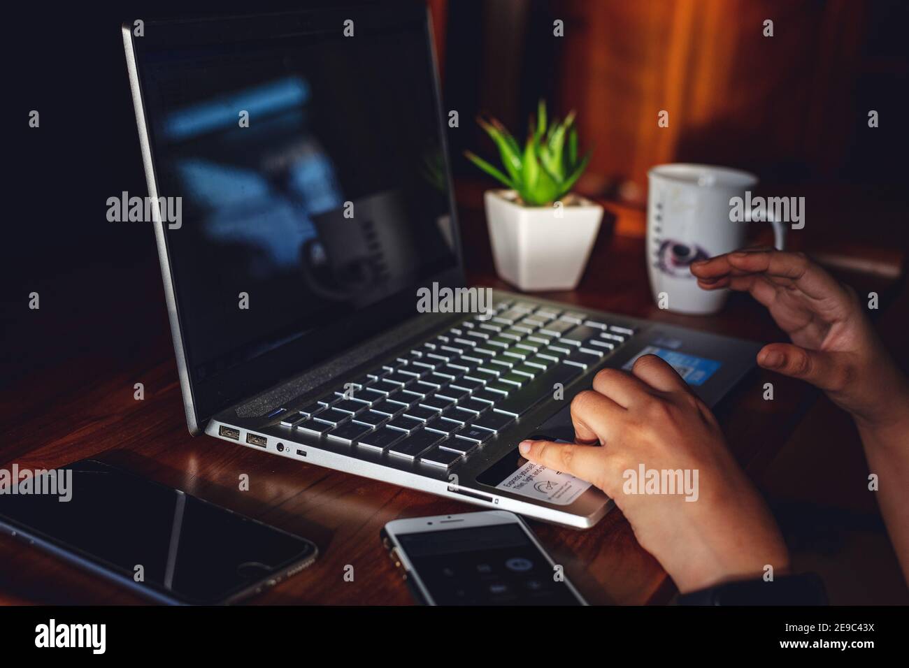 IT professional woman working from home with Laptop and Phones with a hot cup of coffee beside and a green plant Stock Photo